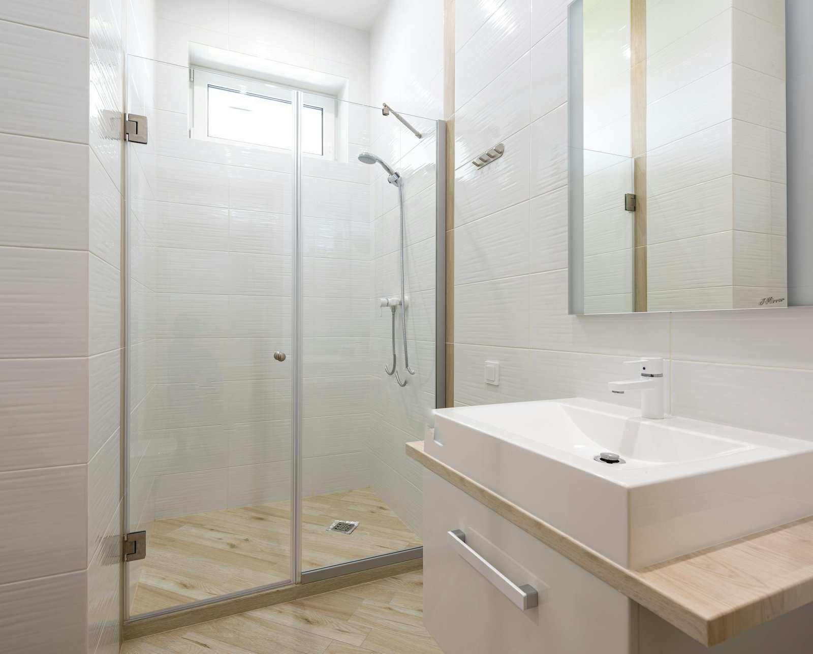 Bright and clean modern bathroom with glass shower and white fixtures.