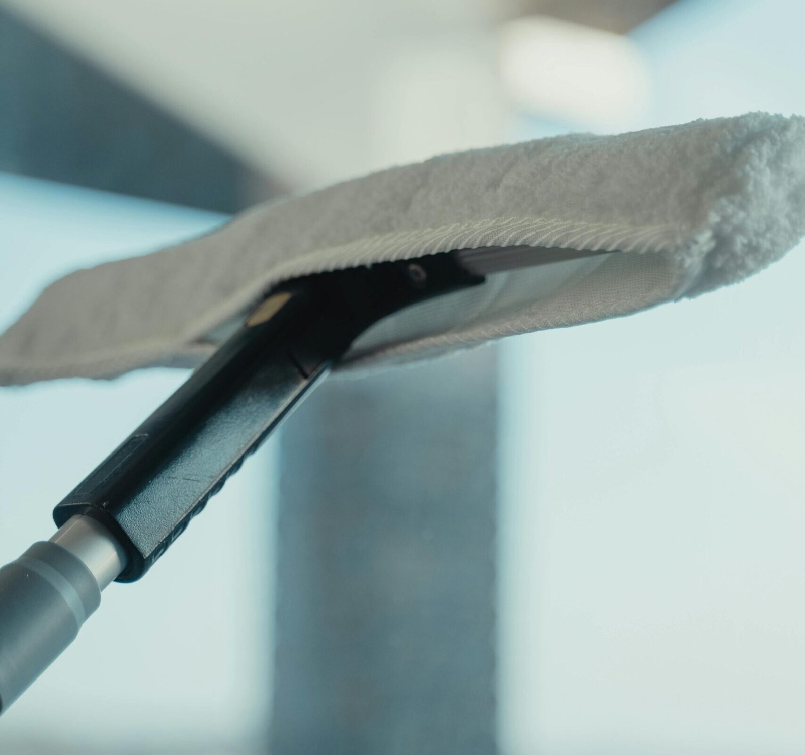 Close-up of a cleaning tool on a window showcasing maintenance and sanitation.